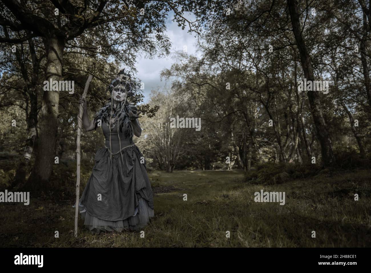 Die Vampirhexe auf dem Streifzug durch die Ruinen und Wälder. Ich trage ein zerrissenes Ballkleid und ein Schädelkopfkostüm Stockfoto