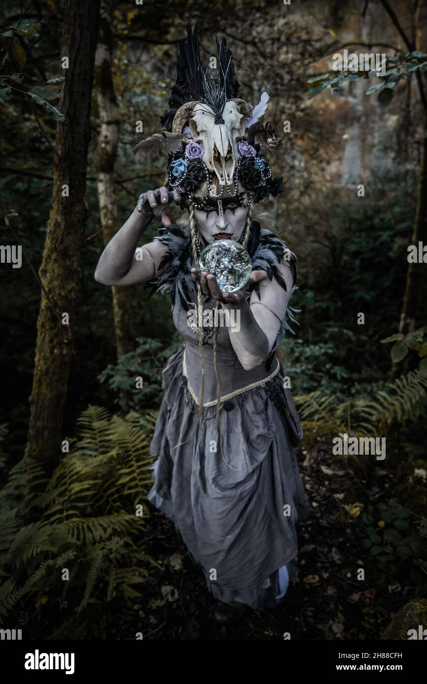 Die Vampirhexe auf dem Streifzug durch die Ruinen und Wälder. Ich trage ein zerrissenes Ballkleid und ein Schädelkopfkostüm Stockfoto
