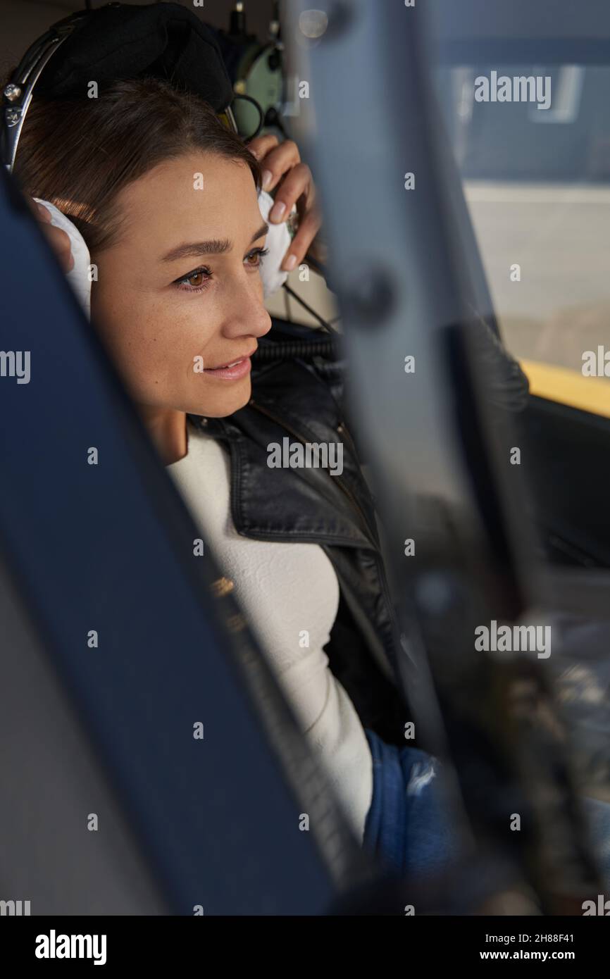 Konzentrierte Dame im Luftfahrt-Headset, die die Straße im Auge behält Stockfoto