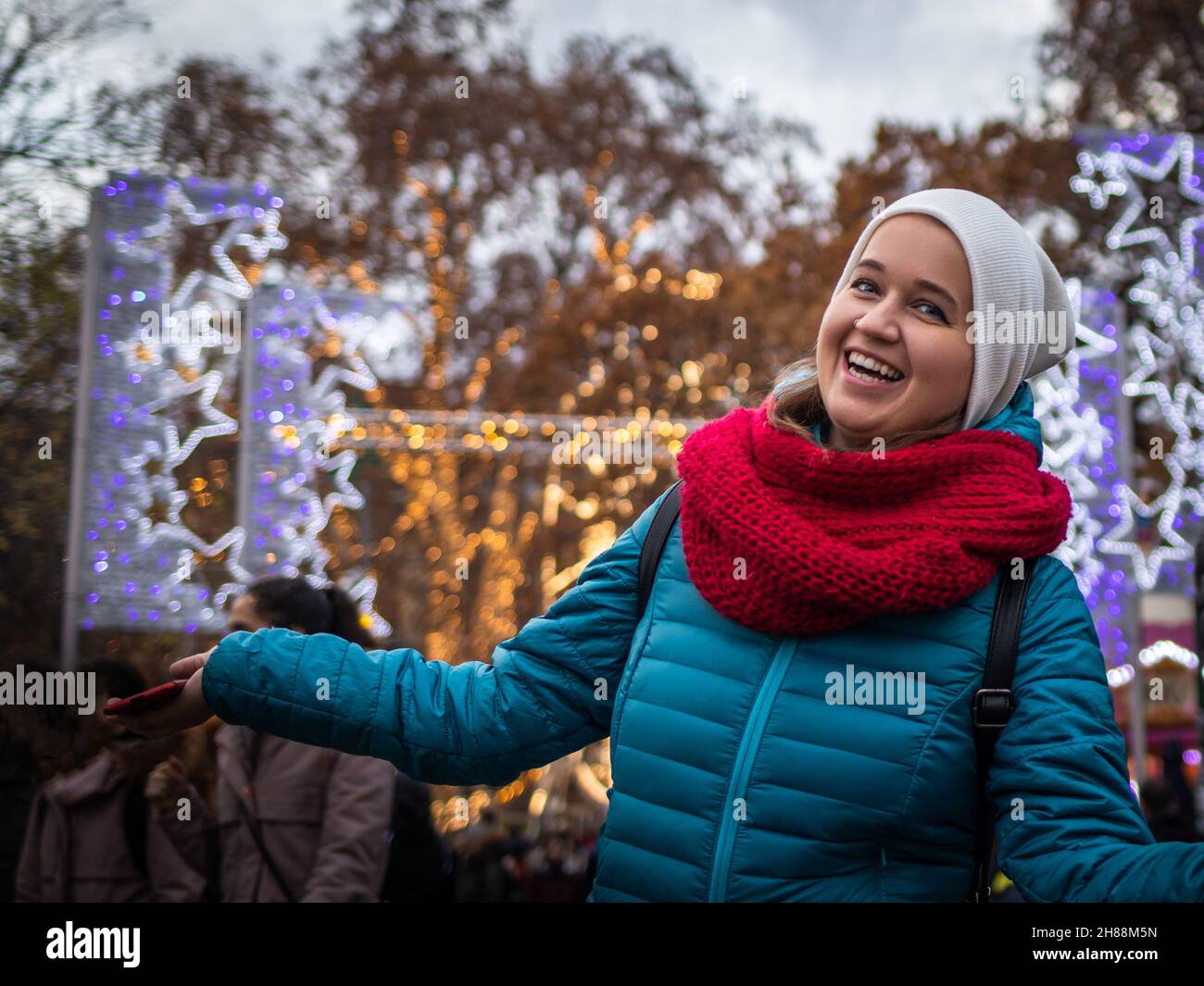 Lächelnde junge Frau auf dem weihnachtsmarkt in Wien, Österreich. Porträt einer kaukasischen Frau, die Weihnachtsferien in der Stadt genießt. Traditionelle Veranstaltung Stockfoto