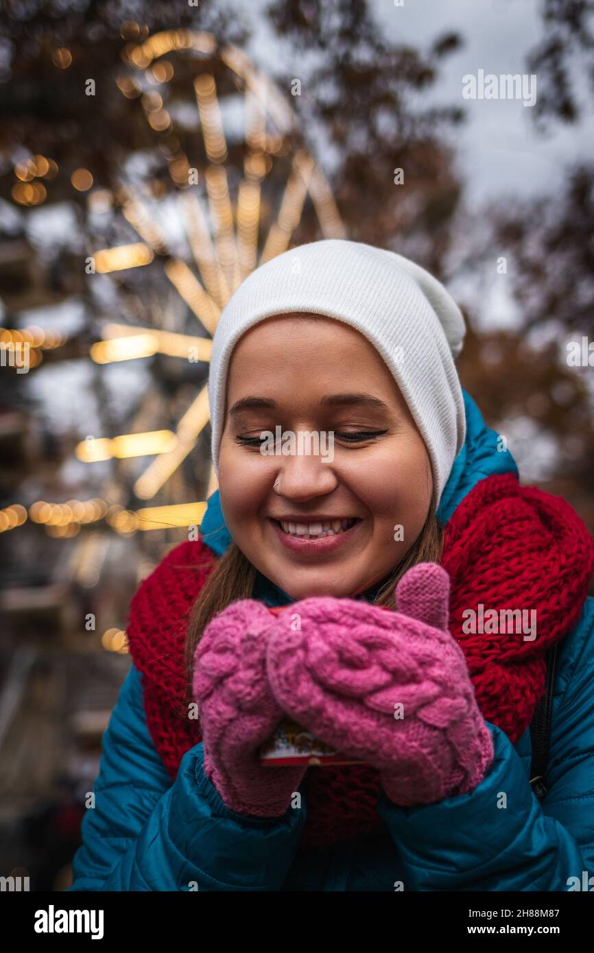 Junge Frau trinkt Glühwein auf dem weihnachtsmarkt in Wien, Österreich. Fröhlicher Tourist, der während der weihnachtsferien Urlaub genießt. Heißes Getränk Stockfoto