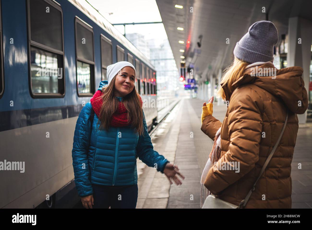 Ich vermisse Euch bereits! Zwei Freundinnen sagen vor der Reise Auf Wiedersehen am Bahnhof. Reisekonzept mit zwei Personen. Eisenbahnverkehr Stockfoto