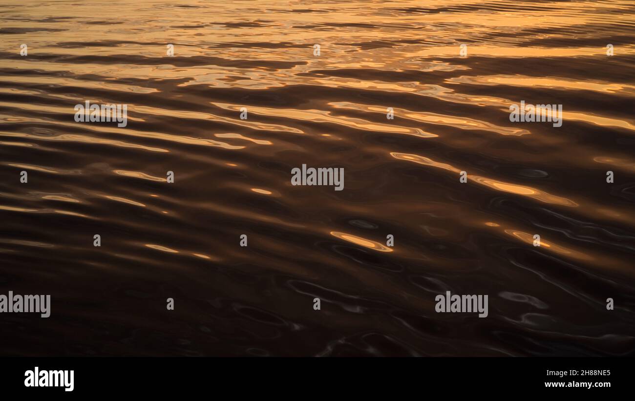 Warme helle abstrakte Wasseroberfläche eines Flusses während des Sonnenuntergangs Stockfoto