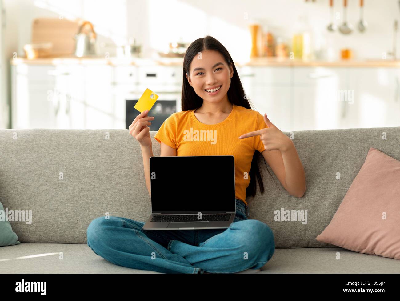 Ferneinkaufskonzept. Glückliche asiatische Frau mit Kreditkarte und Laptop Kauf im Web, mockup Stockfoto