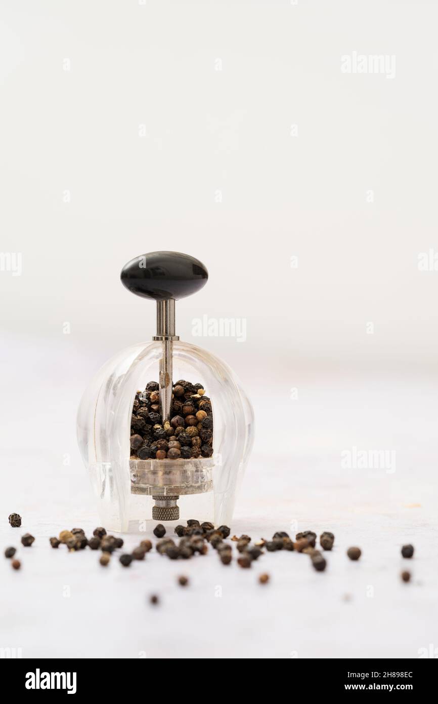 Schwarze Pfeffermühle und Pfefferkörner Stockfoto