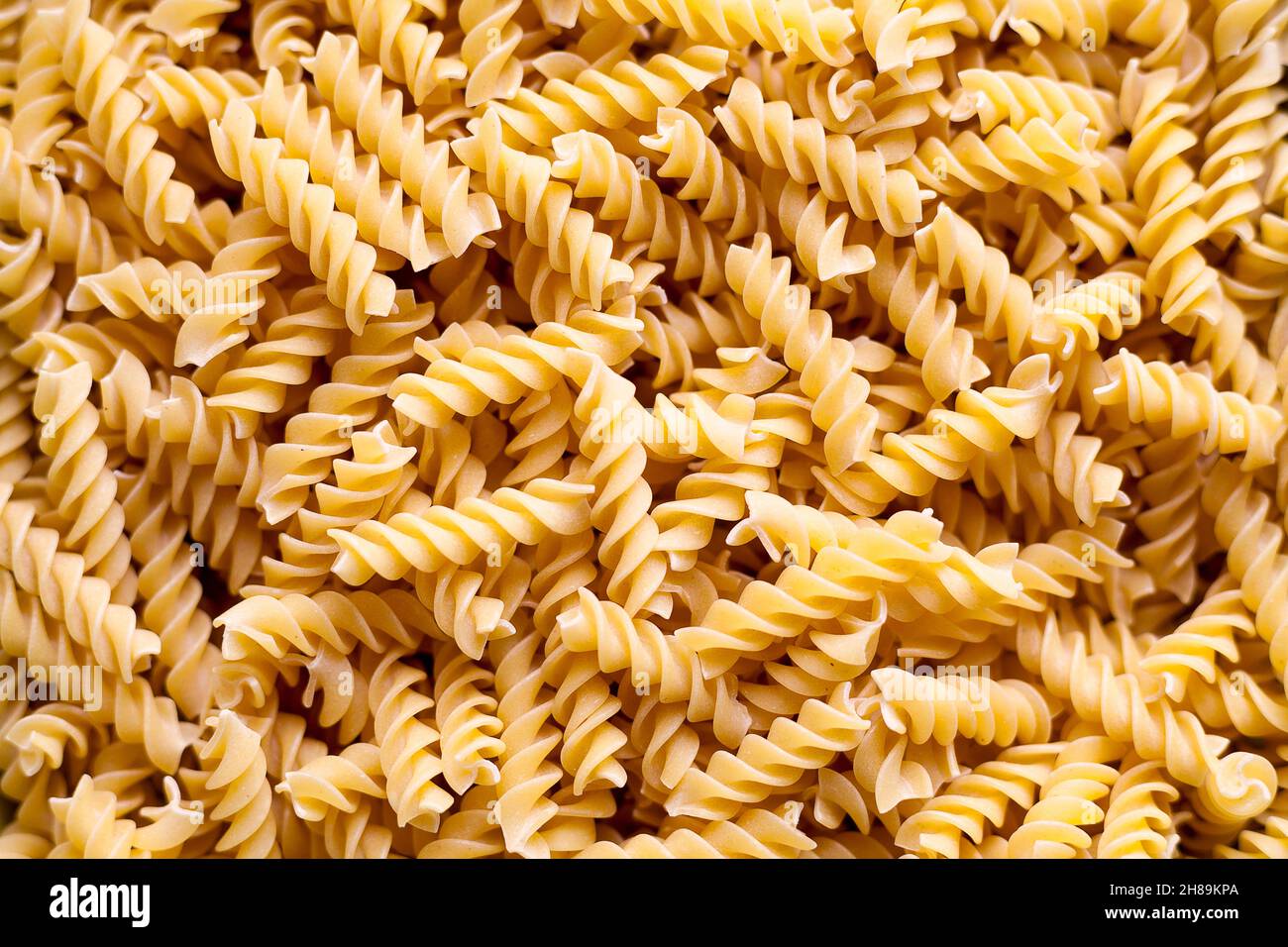 Nahaufnahme im Vollformat auf einem Stapel ungekockter Fusilli. Stockfoto