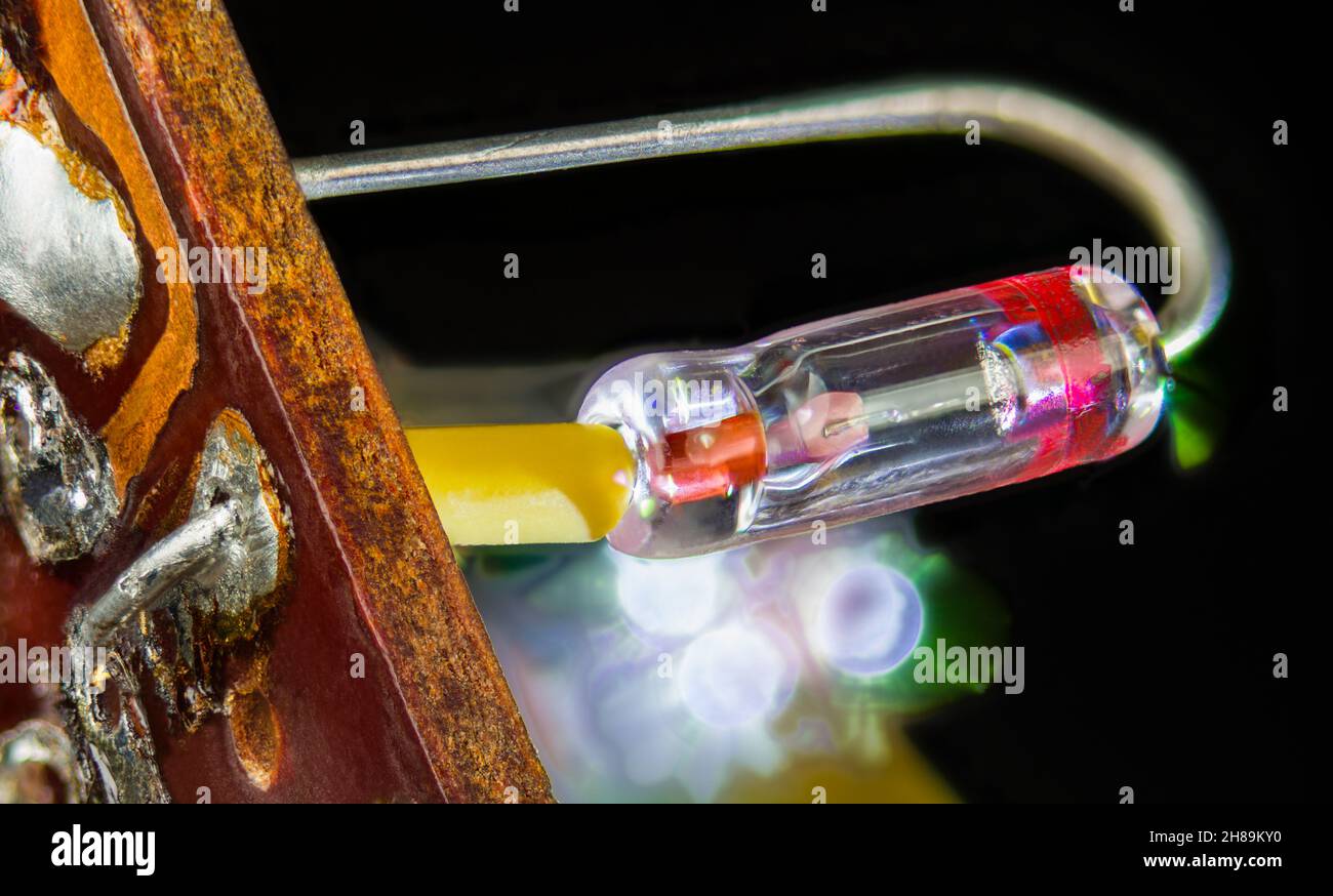 Vintage-Halbleiter-Germaniumdiode mit Kristalldetektor im geschweißten Glasrohr. Nahaufnahme eines in der Leiterplatte gelöteten elektrischen Retro-Bauteils. Stockfoto