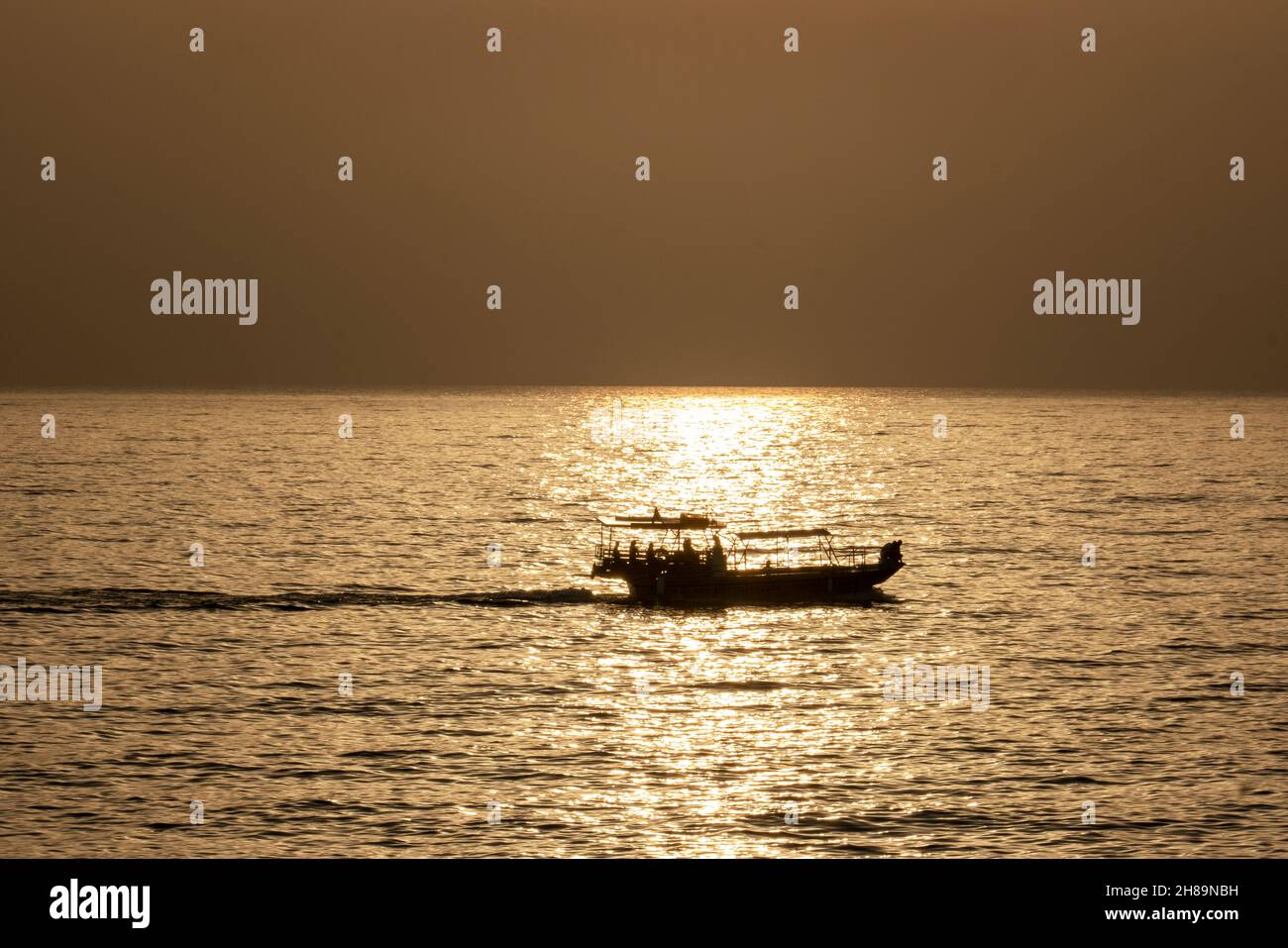 Touristenboot in Silhouette bei Sonnenuntergang vor der Küste von paphos, Zypern. Stockfoto