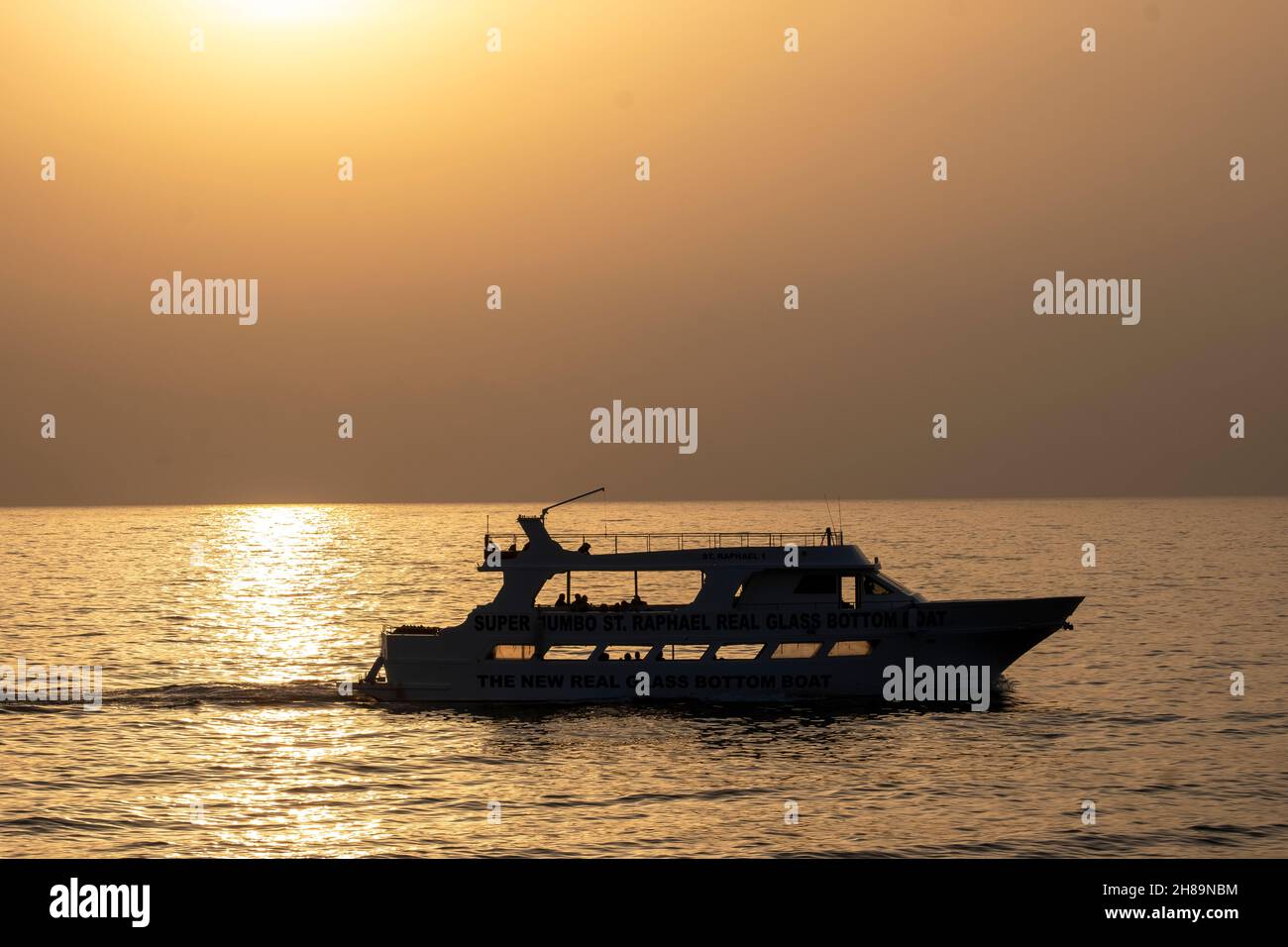 Touristenboot in Silhouette bei Sonnenuntergang vor der Küste von paphos, Zypern. Stockfoto