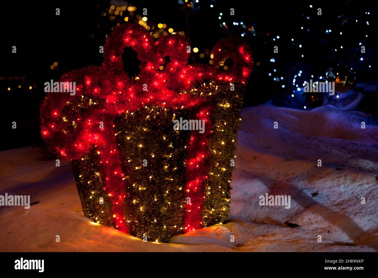 Beleuchtete Weihnachtsdekoration im Freien in Form einer eingepackten Geschenkbox. Stockfoto