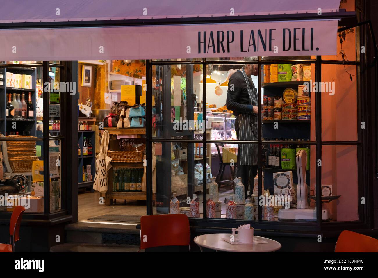 Harp Lane Deli wurde nachts mit Lebensmittelwaren in den Schaufenstern im Stadtzentrum von Ludlow beleuchtet. Shropshire, Großbritannien Stockfoto