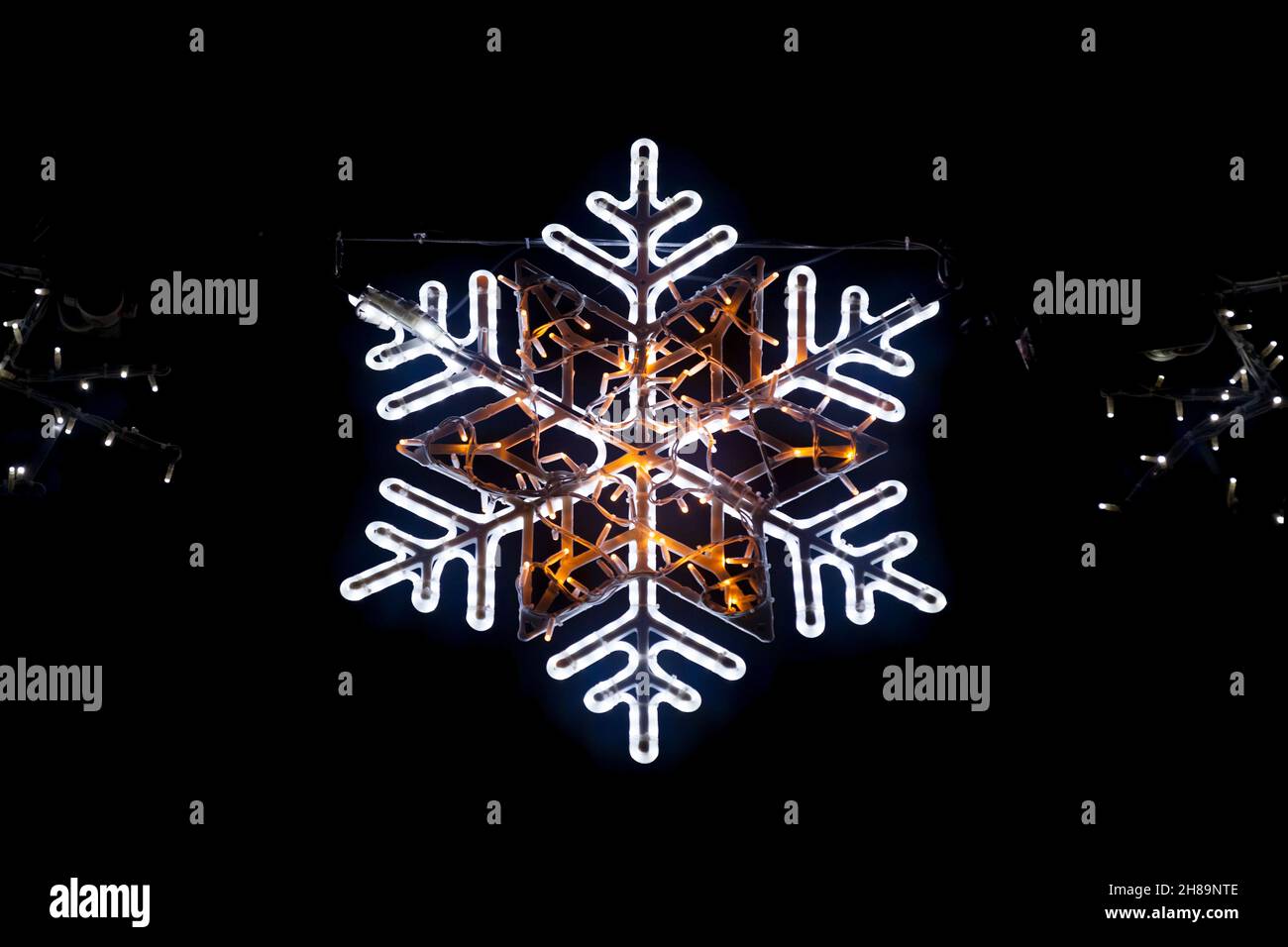 Nahaufnahme eines beleuchteten Schneeflockenlichts aus einer Weihnachtsgirlande. Stockfoto