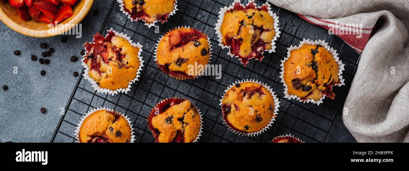 Muffins aus Erdbeerschokolade auf altem Holzständer auf betongrauem Hintergrund. Draufsicht. Stockfoto