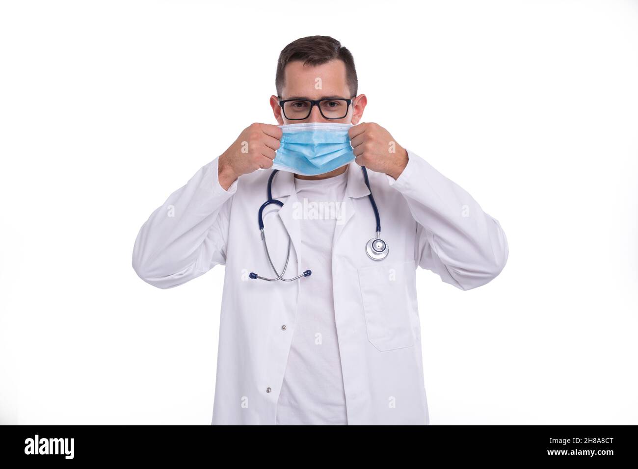 Männlicher Arzt setzt auf medizinische Maske isoliert. Medizinische Arbeitskleidung Des Arztes. Medizinisches Konzept Stockfoto