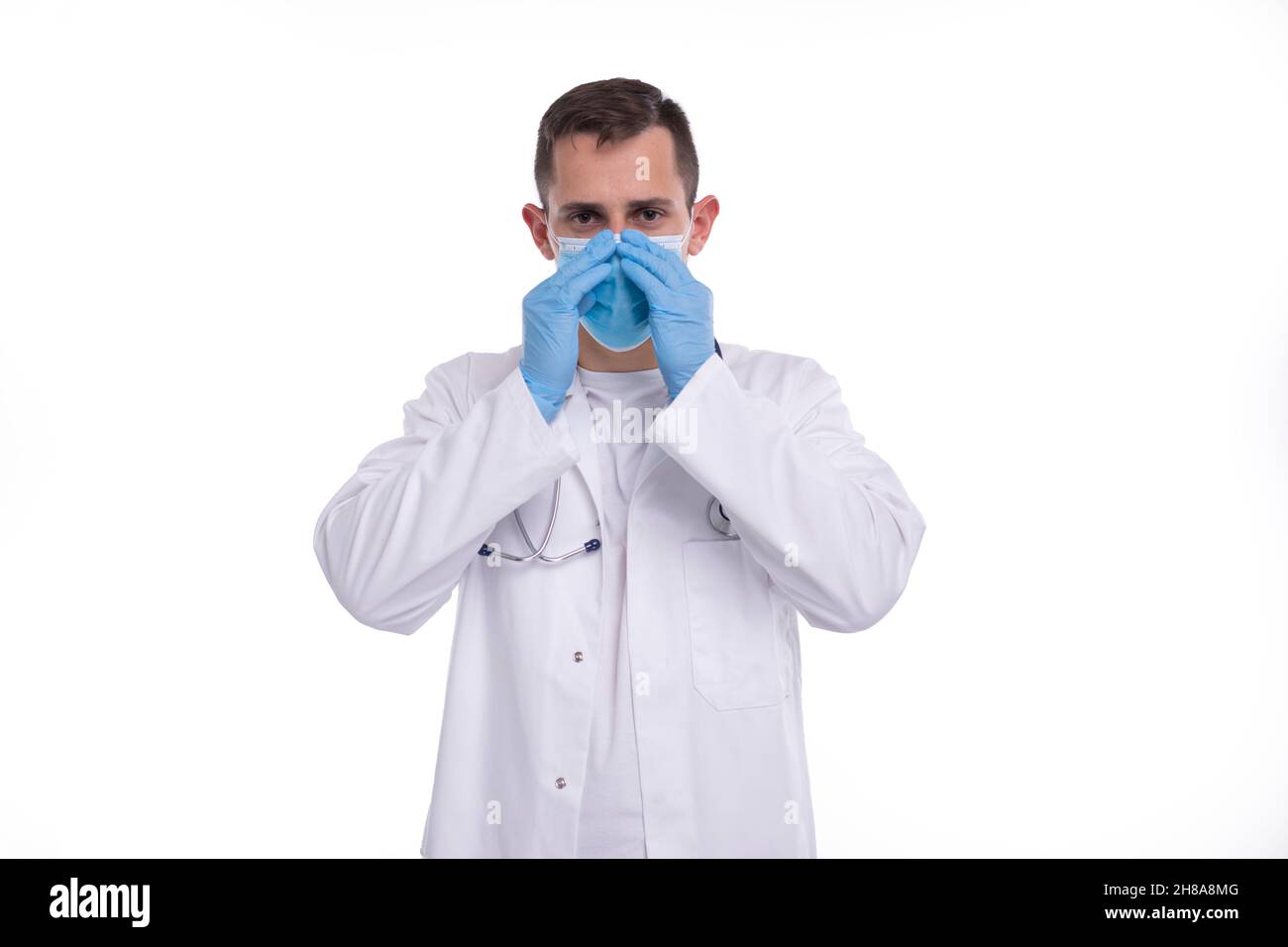 Männlicher Arzt setzt auf medizinische Maske isoliert. Medizinische Arbeitskleidung Des Arztes. Medizinisches Konzept Stockfoto