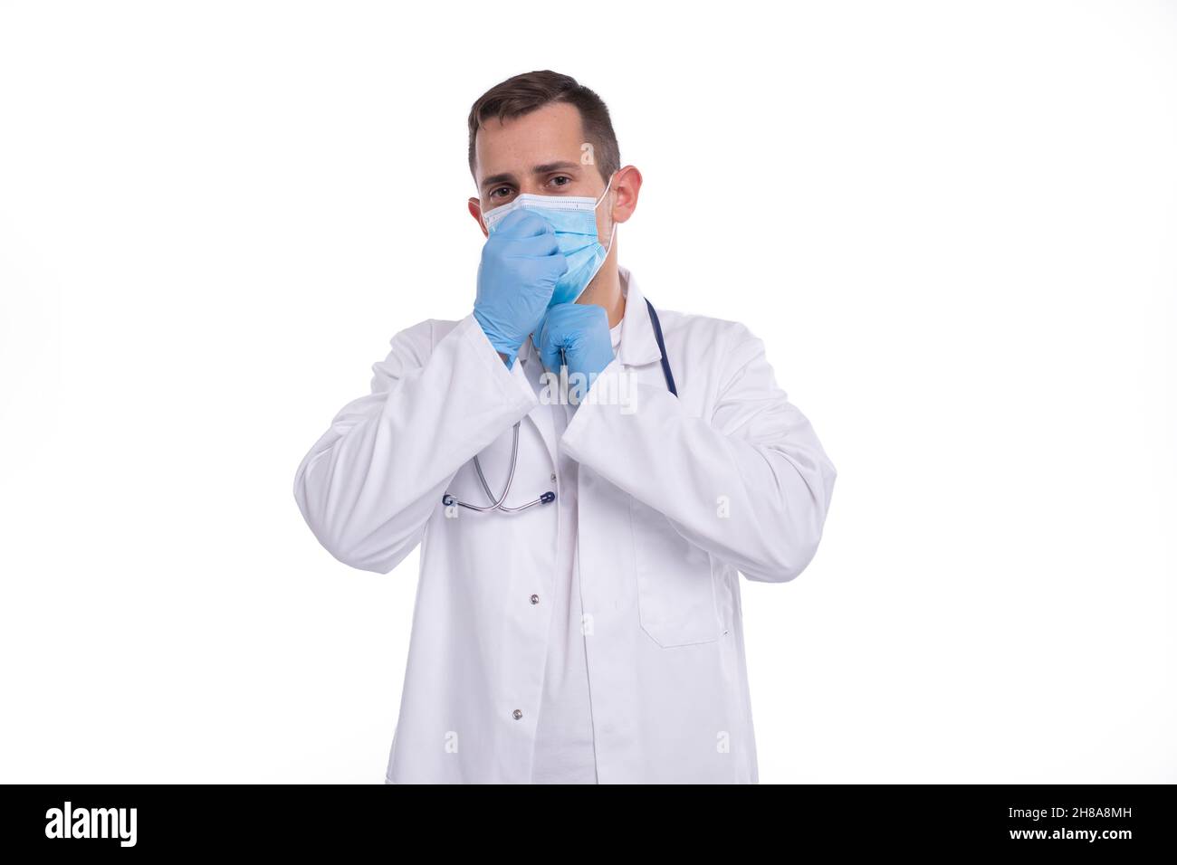 Männlicher Arzt setzt auf medizinische Maske isoliert. Medizinische Arbeitskleidung Des Arztes. Medizinisches Konzept Stockfoto