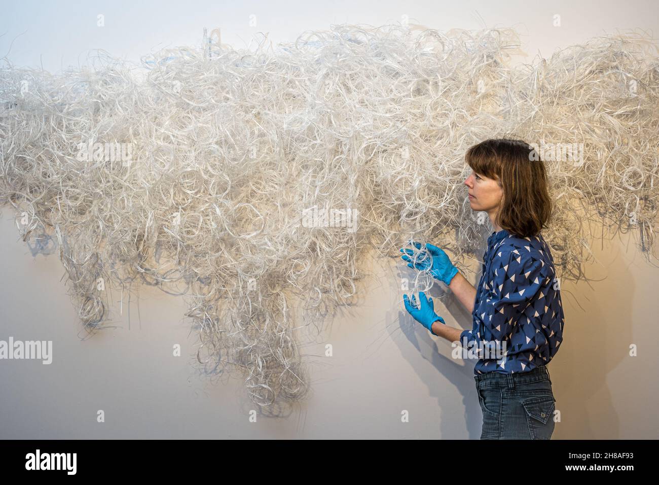 Kuratorin mit recycelten Plastikkunstwerken von Fiona Hutchison in der Tapisserie-Kunstausstellung, City Art Centre, Edinburgh, Schottland, Großbritannien Stockfoto