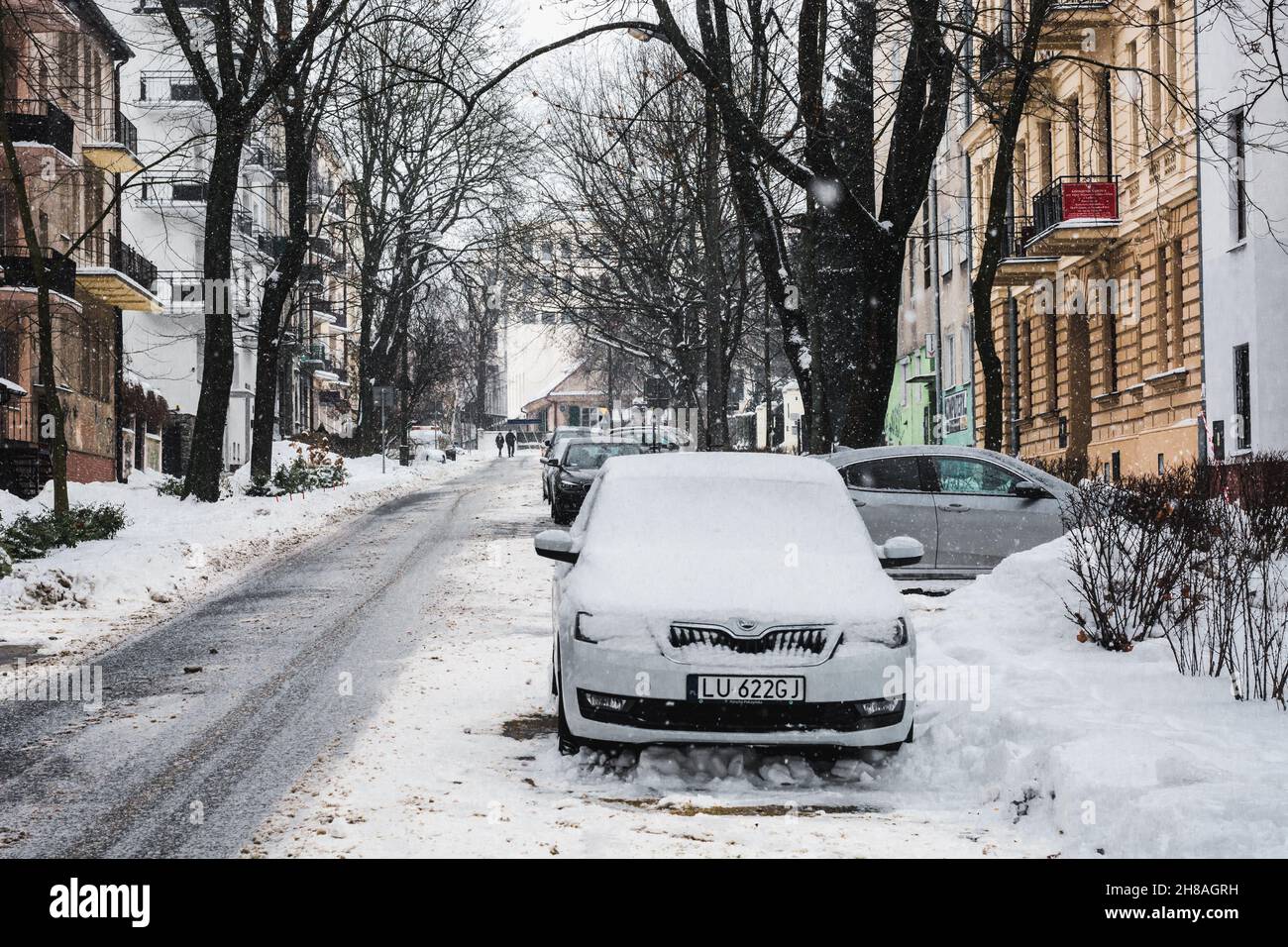 Lublin, Polen - 13. Februar 2021: Schneefall in der Ogrodowa Straße mit geparkten Autos Stockfoto