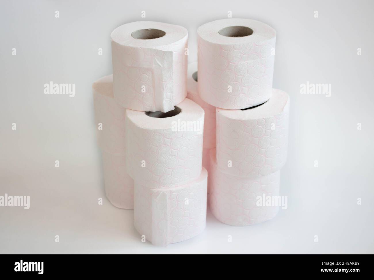 Rosa gemusterter Stapel von weißen Seidenpapierrollen, Toilettenpapierrollen auf weißem Hintergrund Stockfoto
