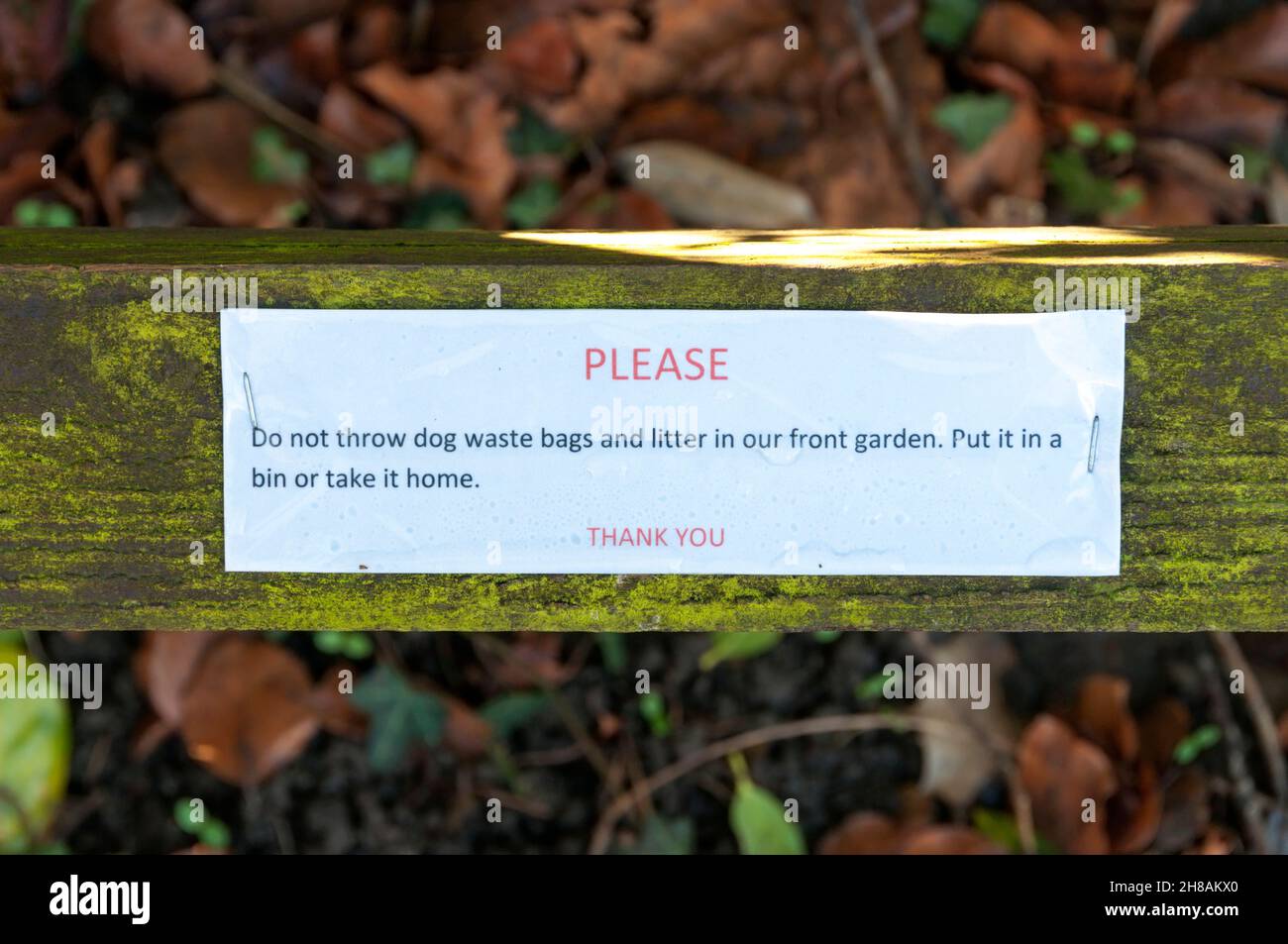 Eine an einen Zaun angeheftete Nachricht fordert, dass die Menschen keinen Müll und Tüten mit Hundemüll in den Vorgarten werfen. Stockfoto