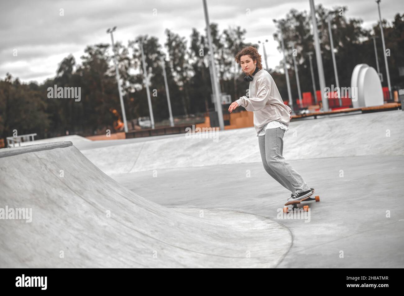 Mädchen mit ausgestreckter Hand auf Skateboard Reiten im Skatepark Stockfoto