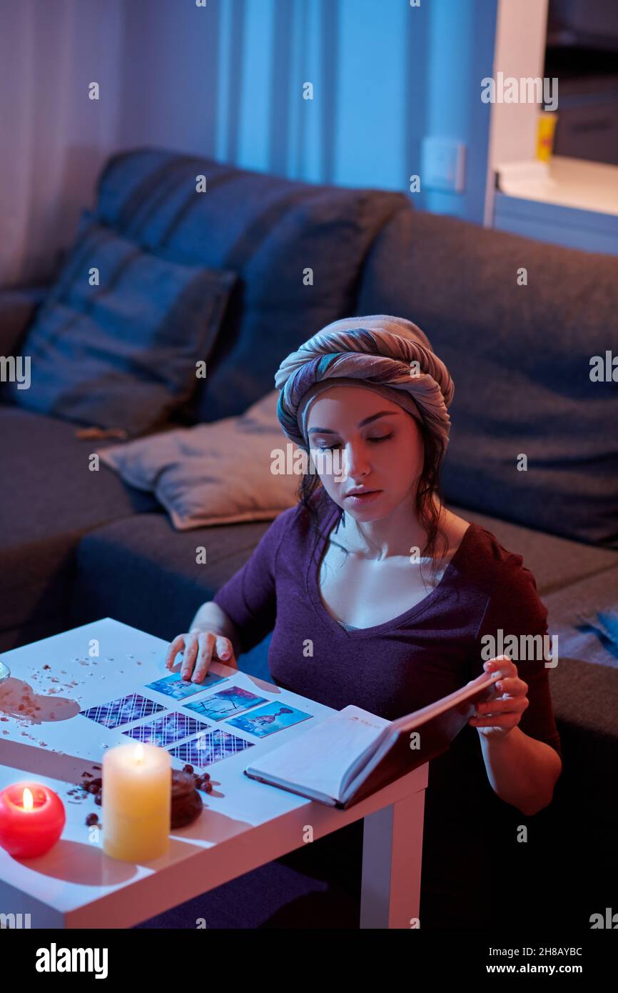 Ernsthafte konzentrierte Frau, die sich auf das Lesen einer Tarot-Karte vorbereitet Stockfoto