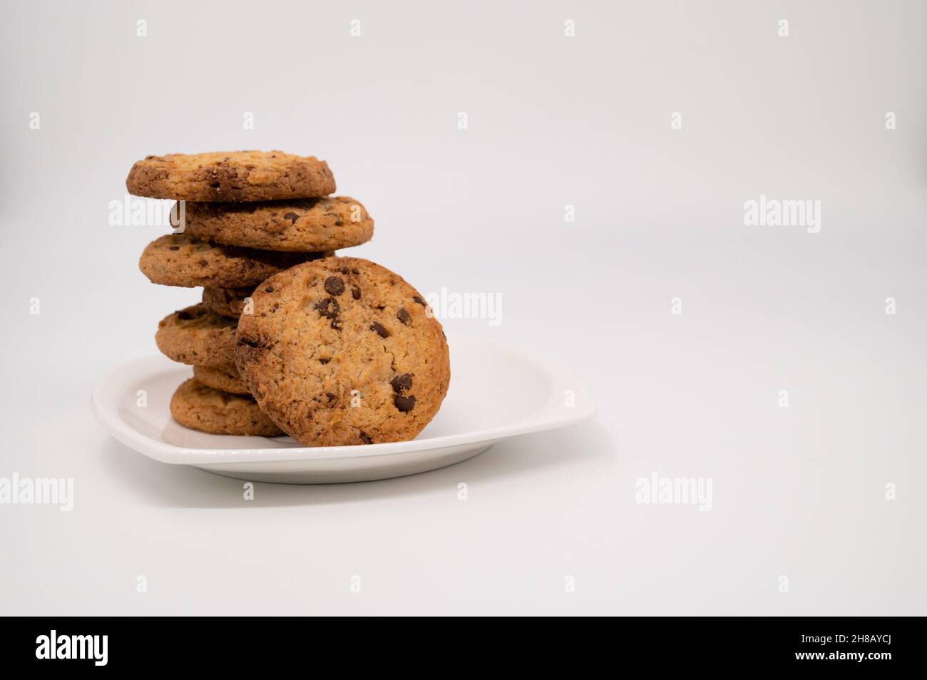 Nahaufnahme eines Lebkuchenkeks mit Schokolade lehnt sich auf einen Stapel auf einem weißen Teller, der auf weißem Hintergrund isoliert ist. Stockfoto