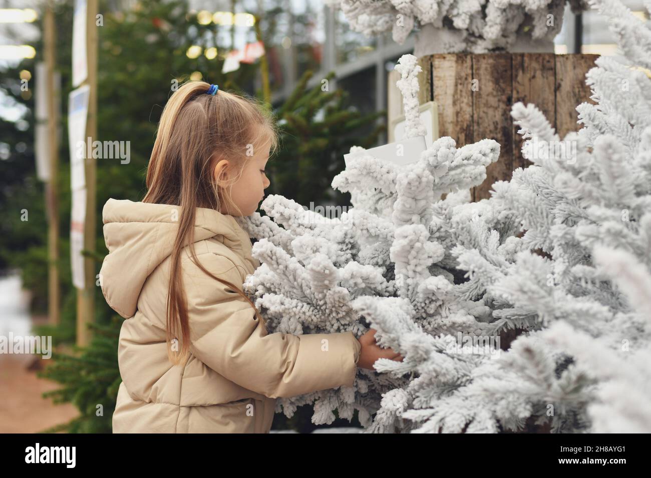 Ein Mädchen und eine weiße weihnachten künstliche Bäume zum Verkauf in einem Geschäft Stockfoto