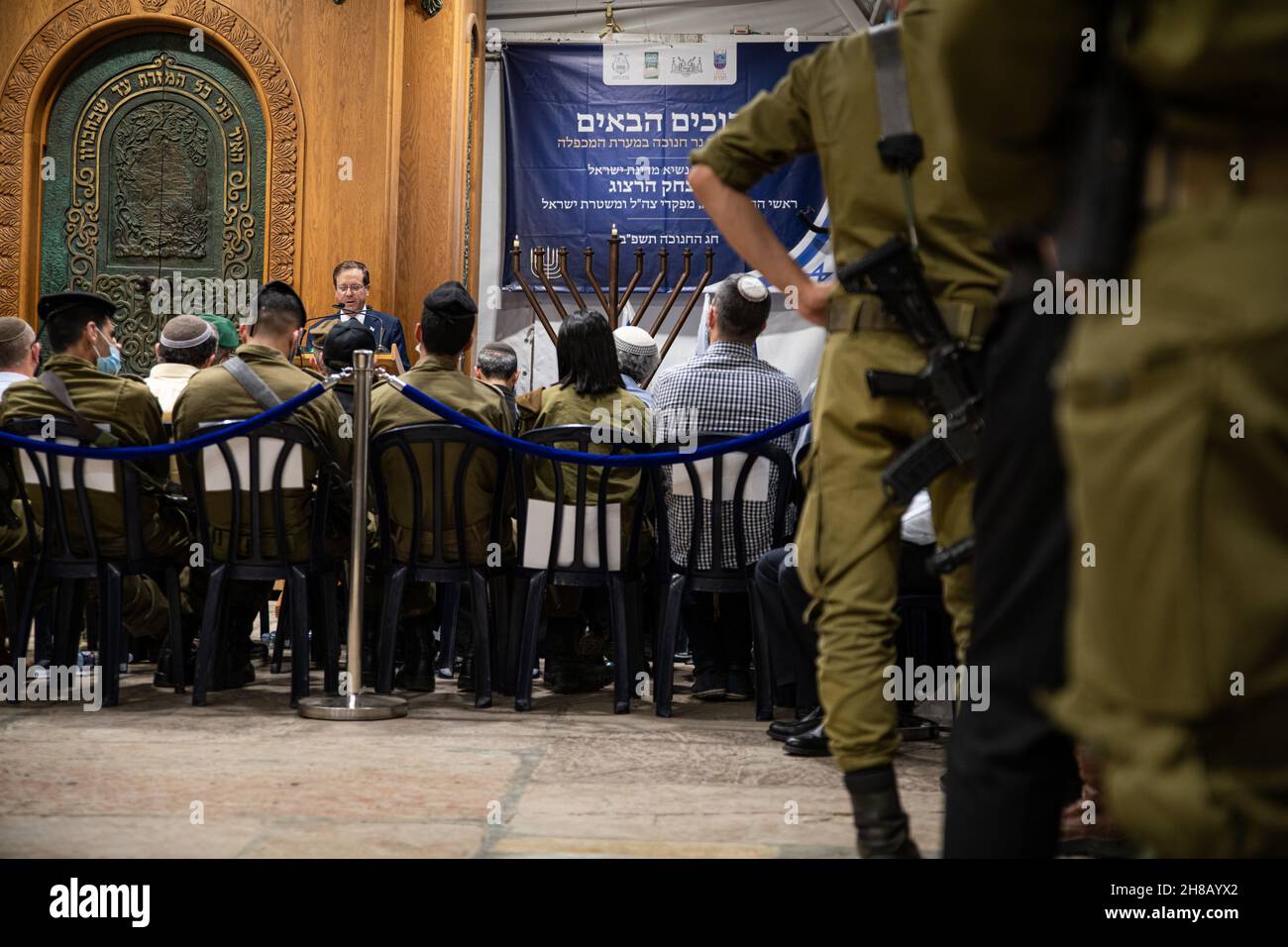 Der israelische Präsident Isaac Herzog zündet bei einer Zeremonie im Grab der Patriarchen, auch bekannt als Ibrahimi-Moschee, die erste Kerze der Chanukka an. Er ist der erste israelische Präsident, der an einer solchen Zeremonie im umstrittenen Kontext der geteilten Stadt Hebron teilnimmt. Linke Organisationen und Aktivisten, die versuchten, vor dem Ort gegen die Beteiligung von Herzog zu demonstrieren, wurden von der IDF und den Polizeikräften am Eingang zum nahe gelegenen Kiryat Arba angehalten - und protestierten am Eingang der Stadt. Hebron, Das Westjordanland. November 28th 2021. (Foto von Matan Golan/Sipa USA) Stockfoto