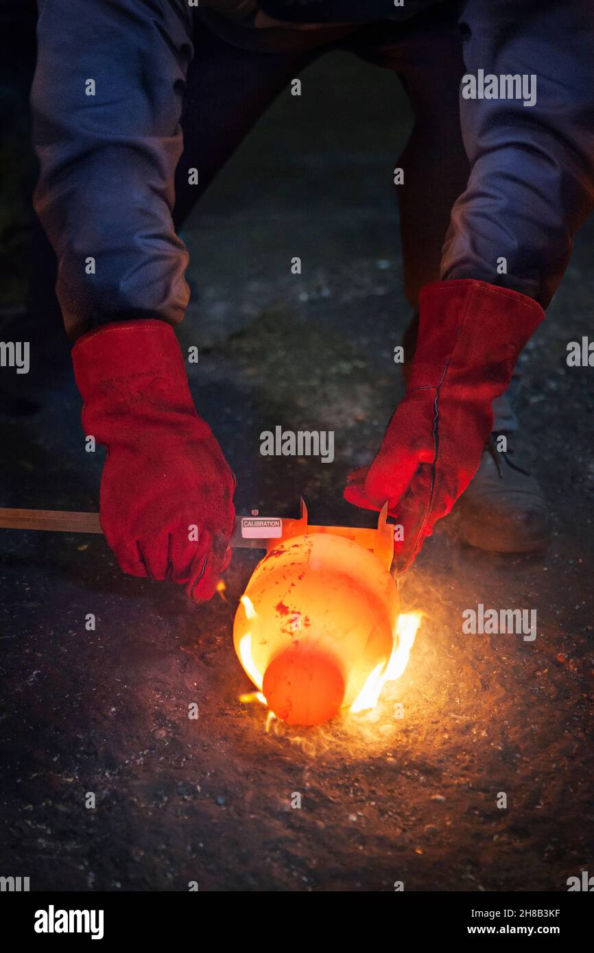 Überprüfung der Durchmesser des einen noch glühenden flammenden Kurbelwelle mit einem Nonius Stockfoto