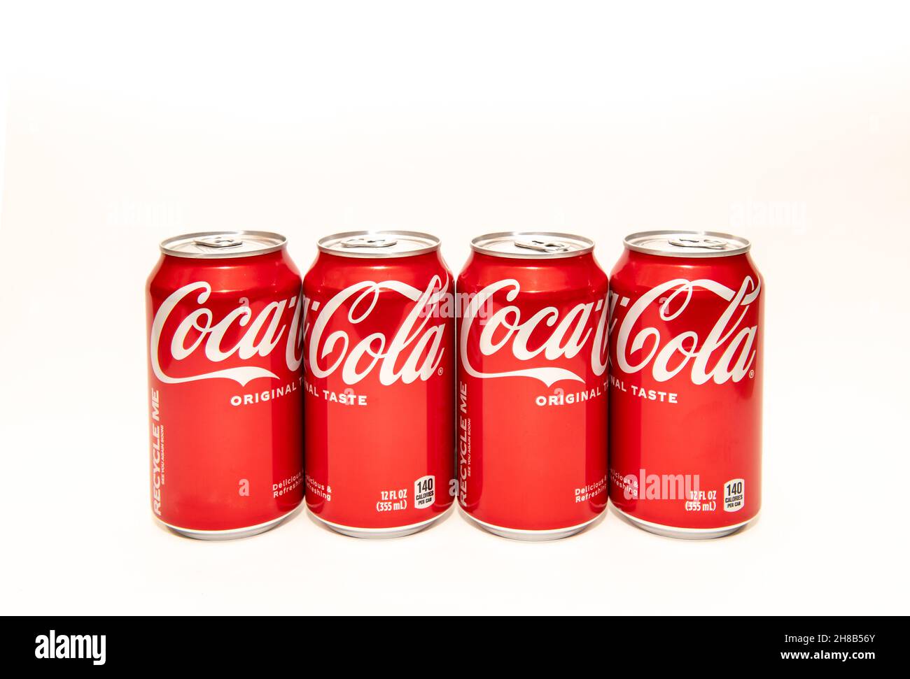 Eine Reihe von vier Dosen Coca Cola, original Taste, auch bekannt als Coke Classic, in traditionellen roten und weißen Dosen. Stockfoto
