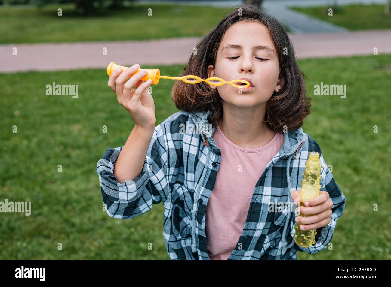 Nette Schülerin der kaukasischen Ethnie bläst Seifenblasen. Porträt eines attraktiven schönen Brünette Mädchen Spaß in einem Sommerpark. Positiv em Stockfoto