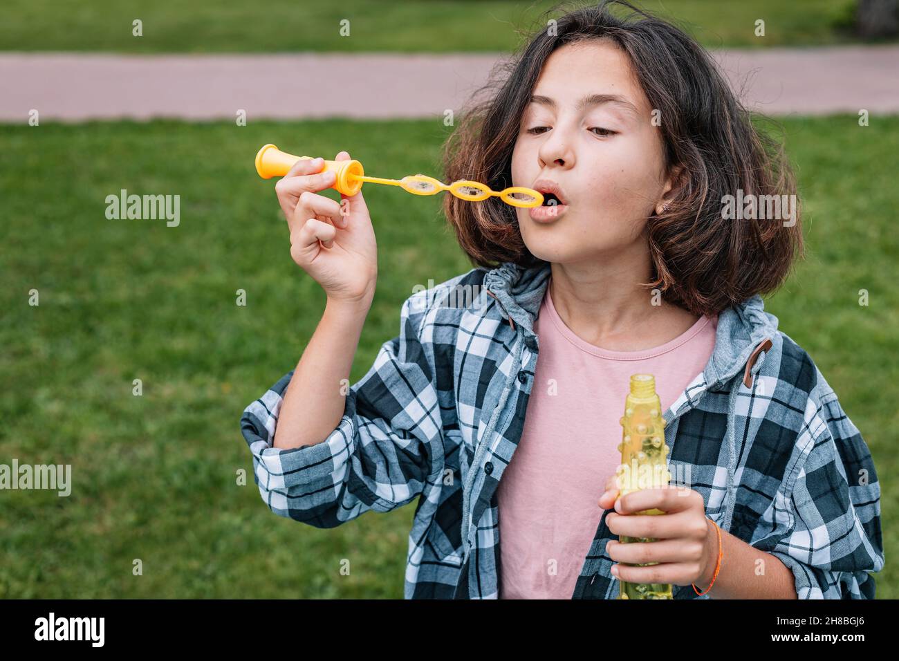 Attraktive Schülerin der kaukasischen Ethnie bläst Seifenblasen. Porträt eines niedlichen schönen Brünette Mädchen Spaß in einem Sommerpark. Positiv em Stockfoto