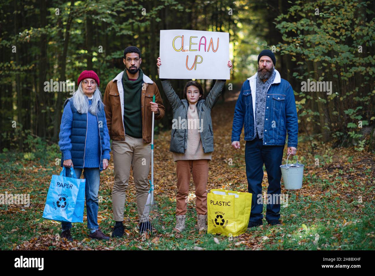 Eine Gruppe von verrugenen Aktivisten, die bereit sind, den Wald zu säubern, Banner in der Hand halten und die Kamera betrachten. Stockfoto