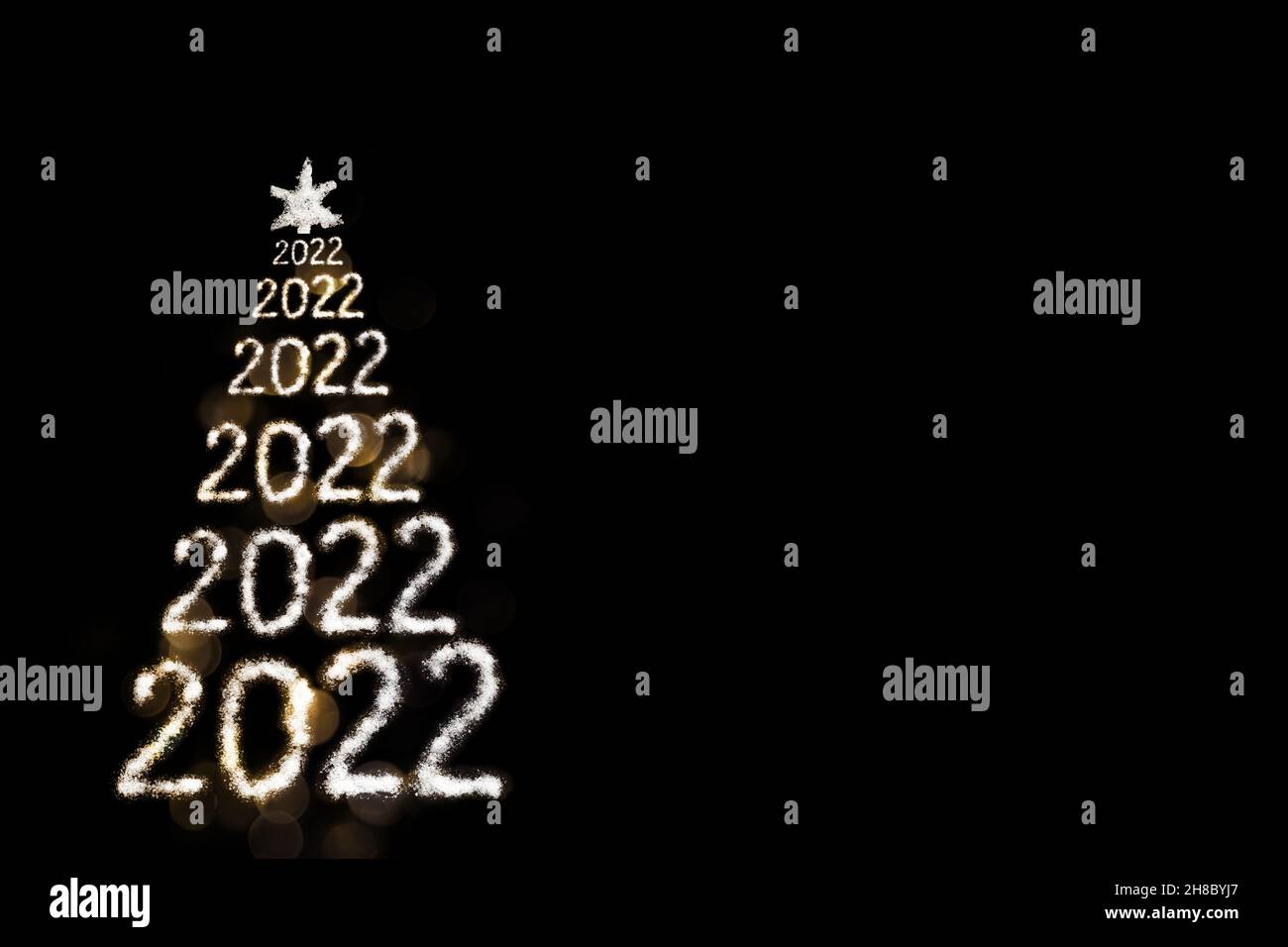 Frohes Neues Jahr 2022. Kreative verschneite Weihnachtsbaum aus Zahlen 2022 und Stern isoliert auf schwarzem Hintergrund mit Bokeh. Ein handgefertigter Weihnachtsbaum Stockfoto