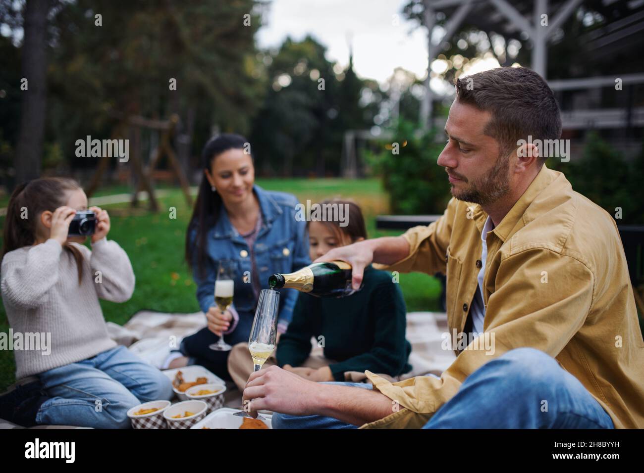 Glückliche junge Familie, die auf einer Decke sitzt und im Restaurantbereich ein Picknick zum Mitnehmen macht. Stockfoto