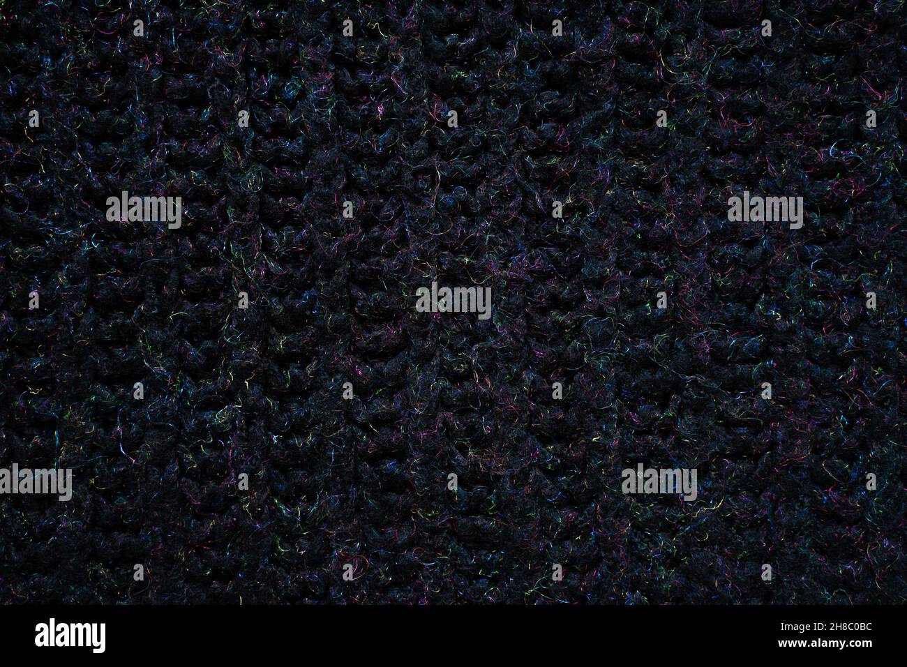 Schwarz gestricktes Textil mit mehrfarbigem Regenbogen-Metallic-Faden Hintergrund. Kunstvolle Urlaubstruktur aus Wolle Stockfoto
