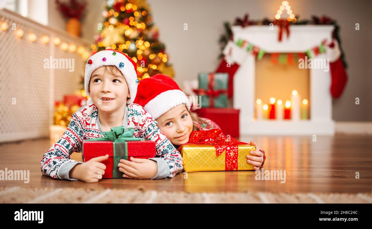 Glückliche Kinder liegen im Wohnzimmer zu Hause im weihnachts-Pyjama Stockfoto
