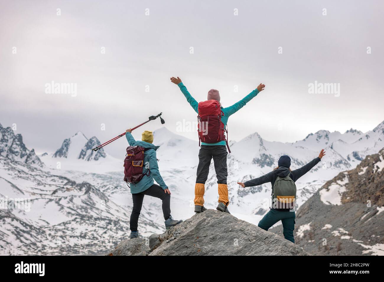 Drei glückliche Wanderinnen stehen mit offenen Armen in den Bergen und blicken auf den Gletscher Stockfoto