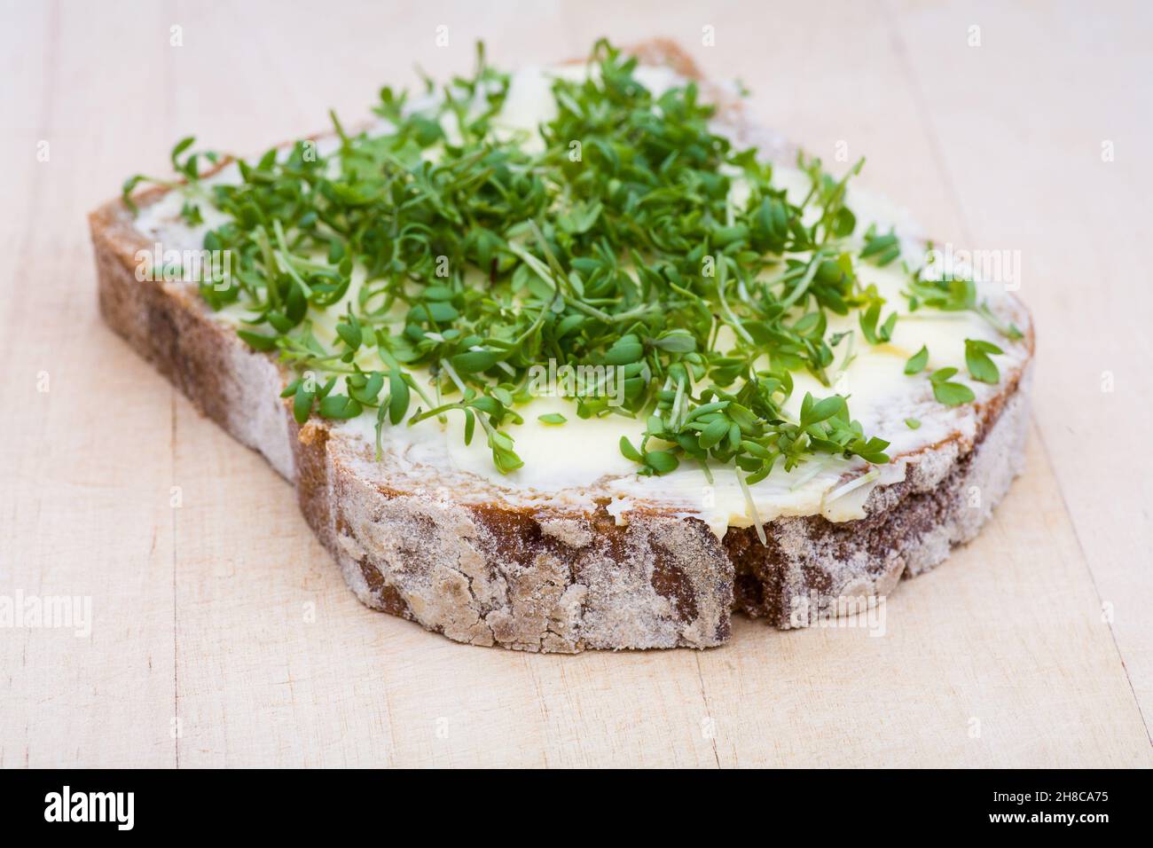 Brot mit Butter und Kresse auf einem Holzbrett Stockfoto