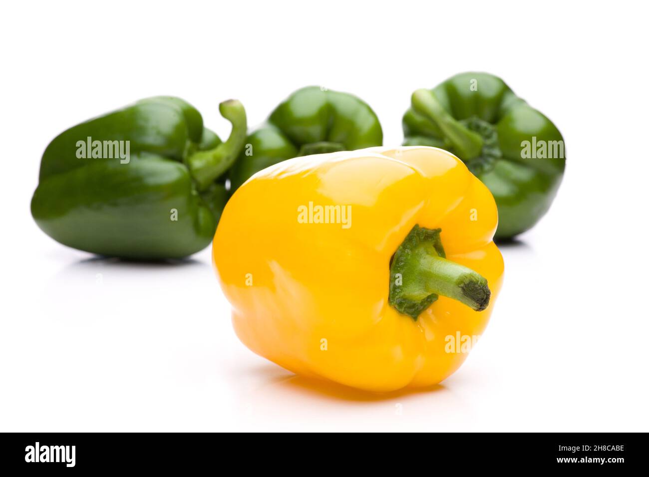 Gelbe Paprika gegen drei grüne Paprika Stockfoto