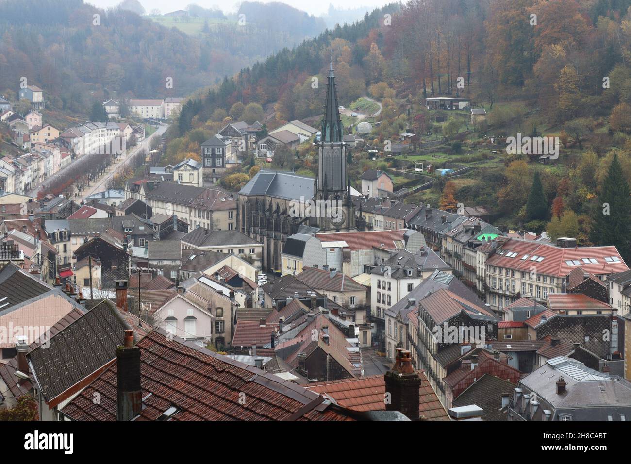 Blick auf den historischen Kurort Plombières-les-bains, in Vosges, Frankreich, an einem nebligen Herbsttag. Von den umliegenden Hügeln aus hat man einen Blick in den hohen Winkel. Stockfoto