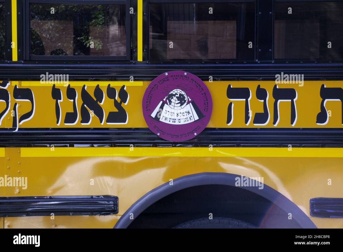 Ein Schulbus mit hebräischem Logo für die jüdische Gruppe Sanz Klausenburg mit chassidischem Namen. In Williamsburg, Brooklyn, New York City. Stockfoto