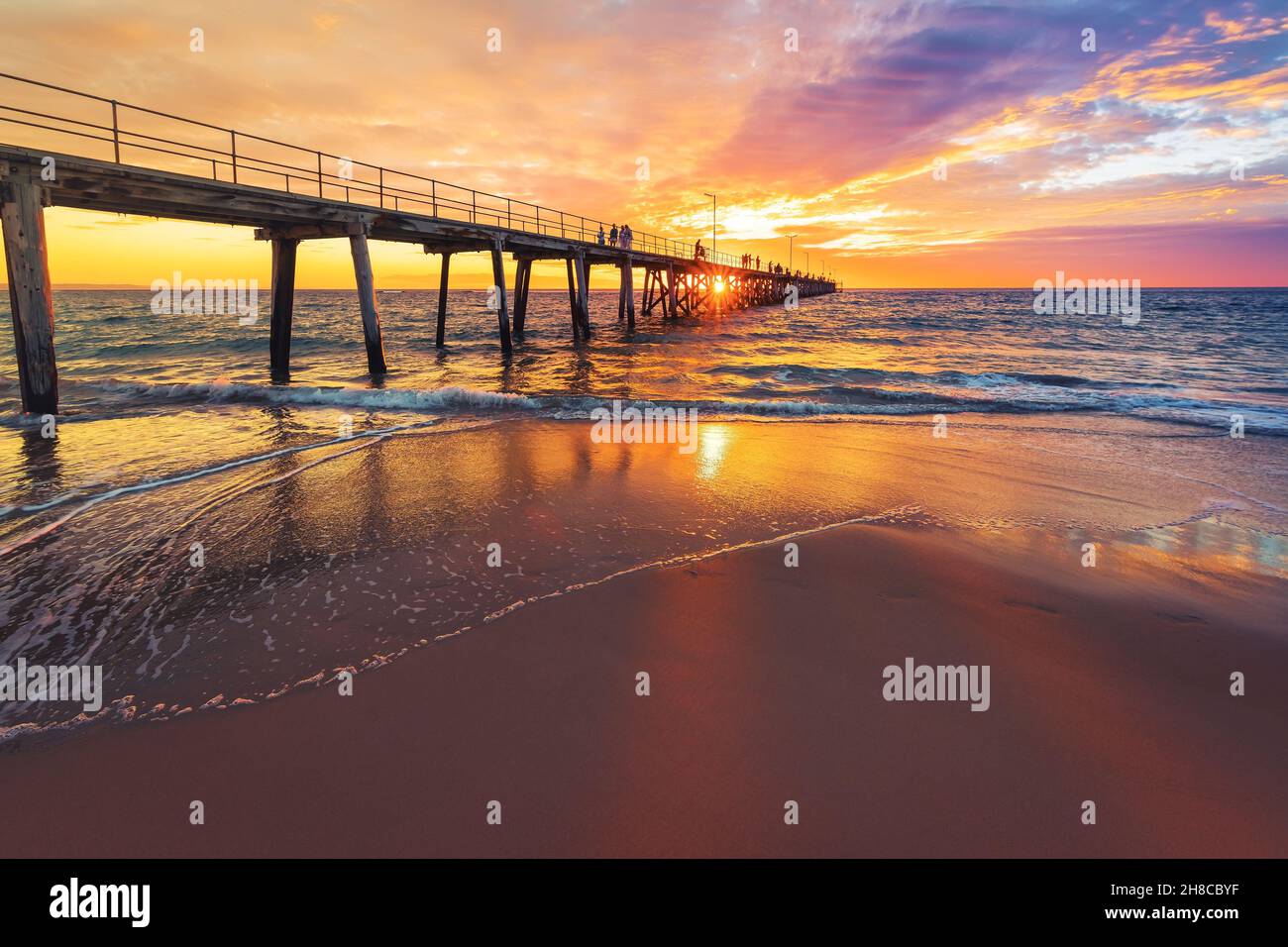 Port Noarlunda Beach Pier mit Menschen, die bei Sonnenuntergang entlang gehen, South Australia Stockfoto