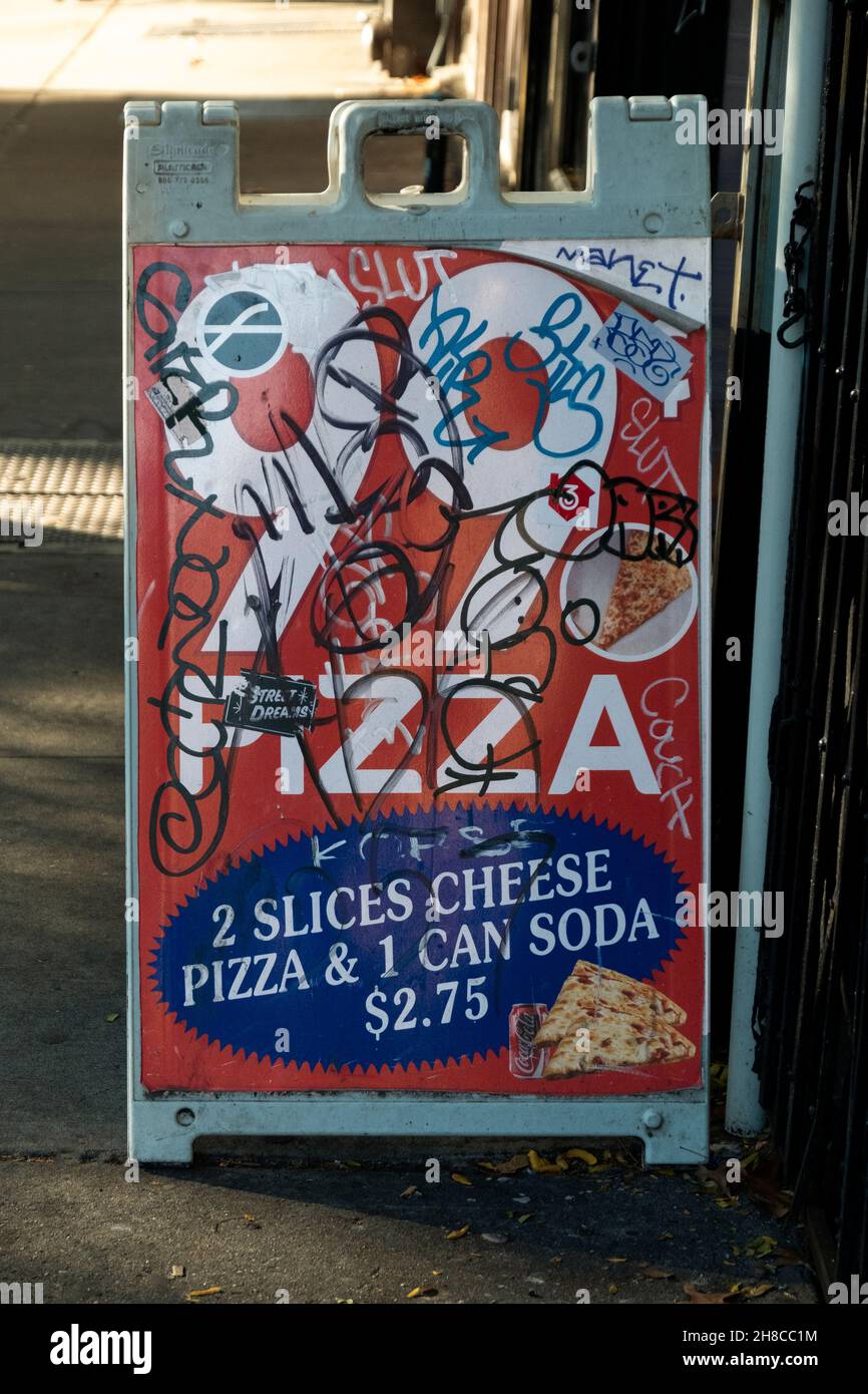 Ein sDefaced Schild vor einem Rabatt Pizzalabor auf der Avenue A im East Village, Manhattan, New York City. Stockfoto