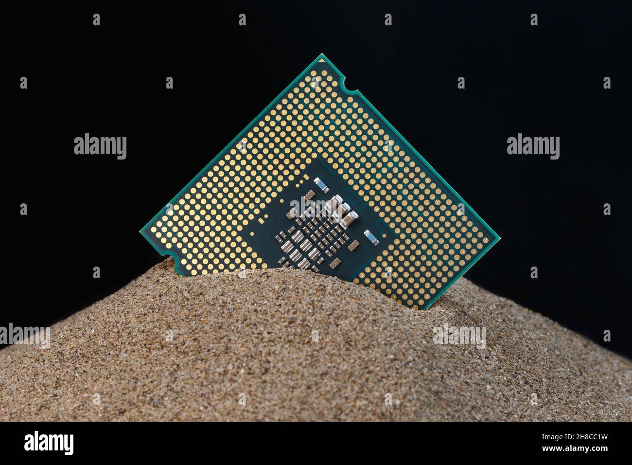 Mikroprozessor ragt aus dem Sand. Konzept zur Herstellung von Silizium-Halbleitern aus Sand. Stockfoto