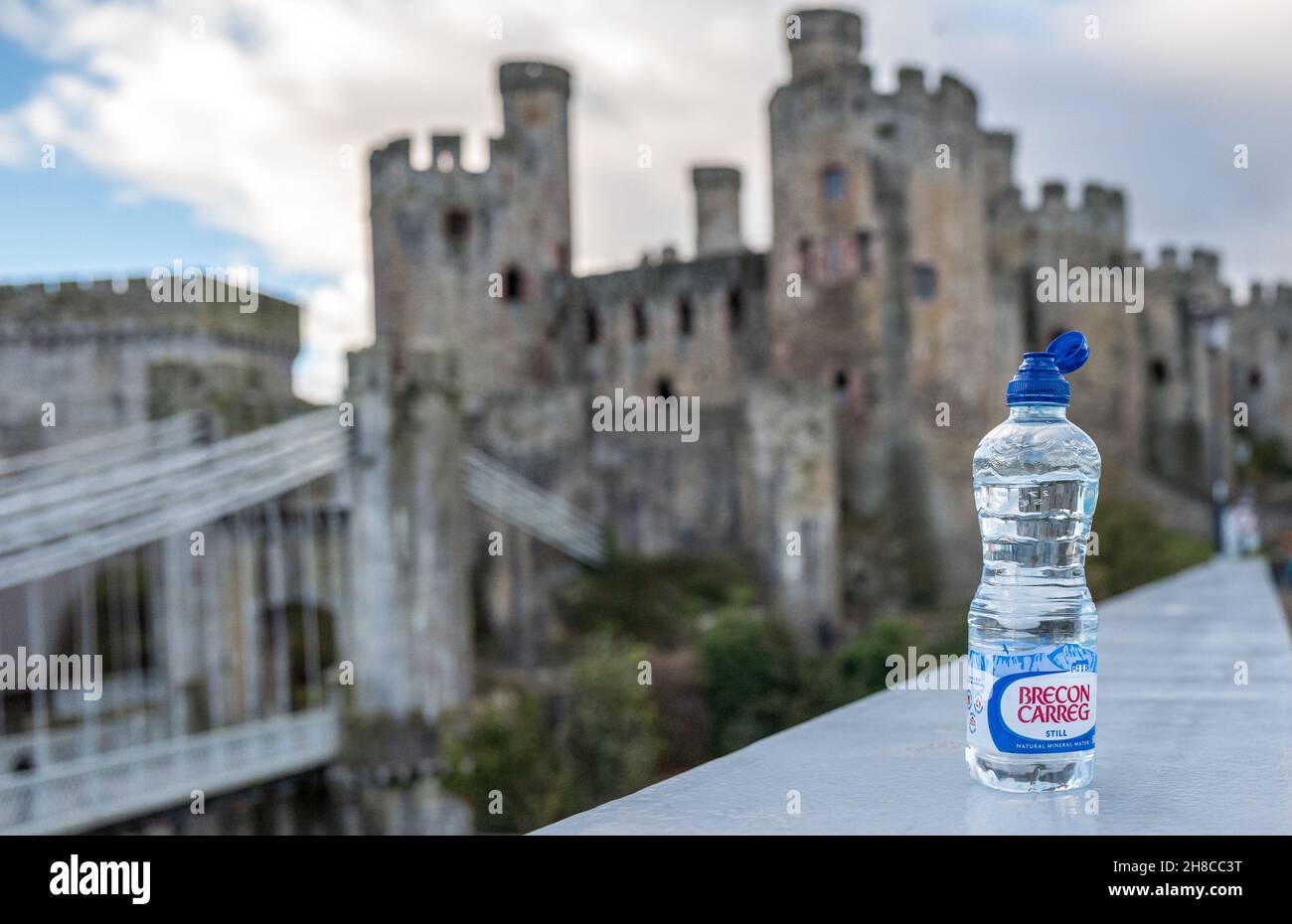 Plastikflasche Brecon Carreg noch Mineralwasser mit Conwy Schloss im Hintergrund. Stockfoto