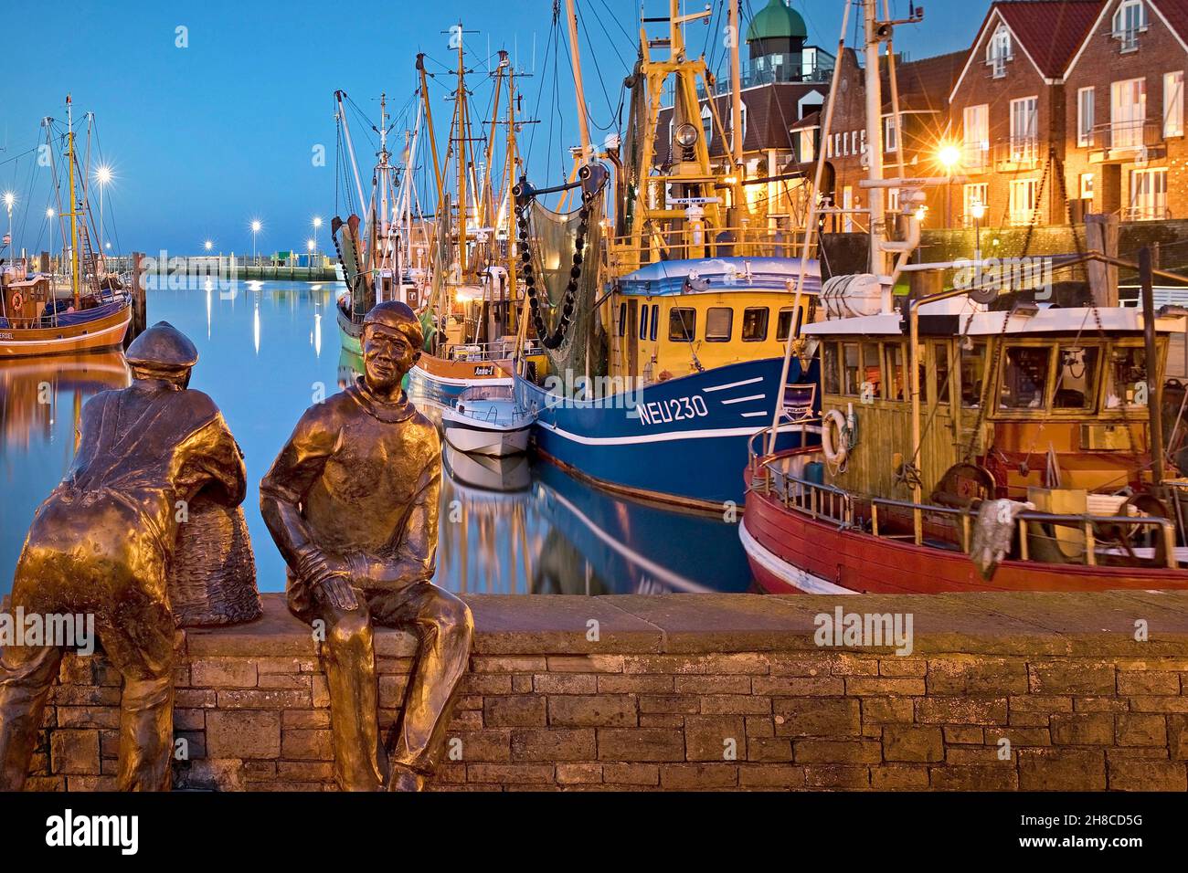 Fischerhafen mit Garnelen und Skulptur Alt- und Jungfischer am Abend, Deutschland, Niedersachsen, Neuharlingersiel Stockfoto