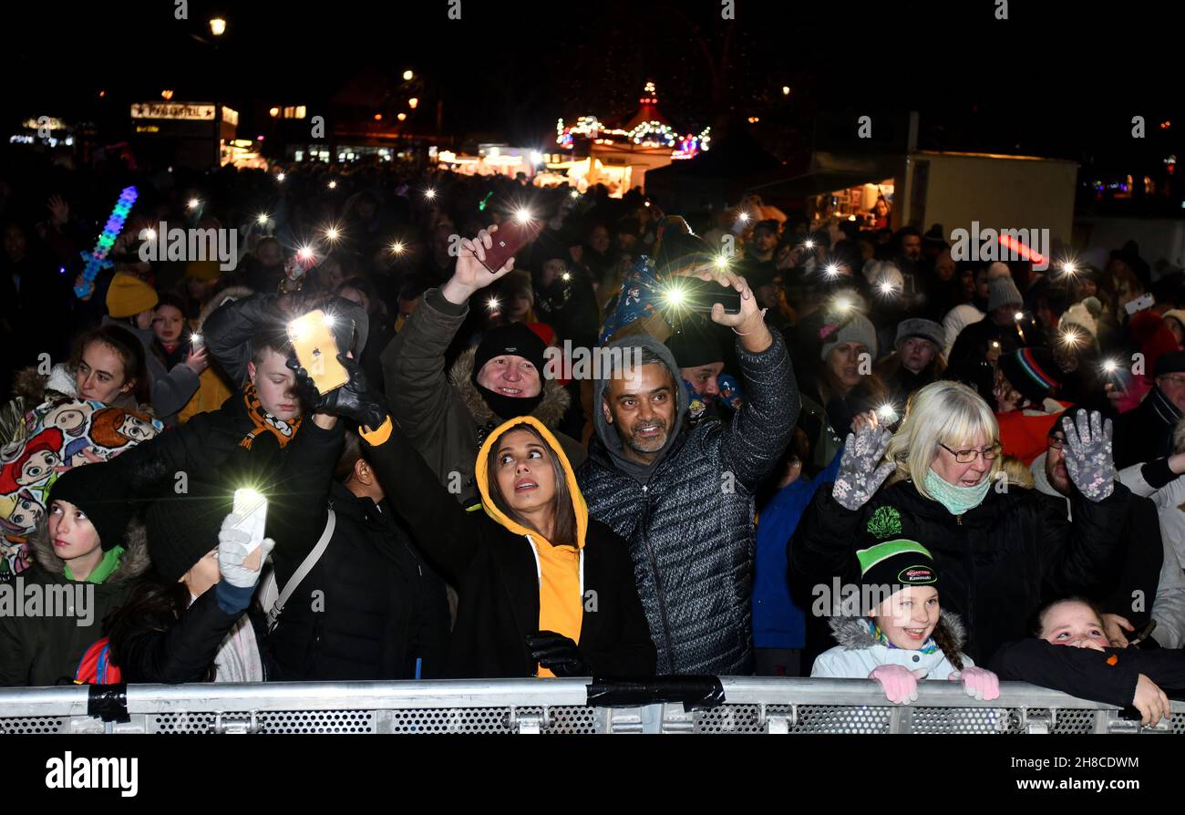 Die Bewohner der Weihnachtsgemeinschaft winken mit ihren Handy-Lichtern Fackeln, um das Einschalten der Weihnachtsbeleuchtung in Tettenhall, Wolverhampton, 2021, zu feiern Stockfoto