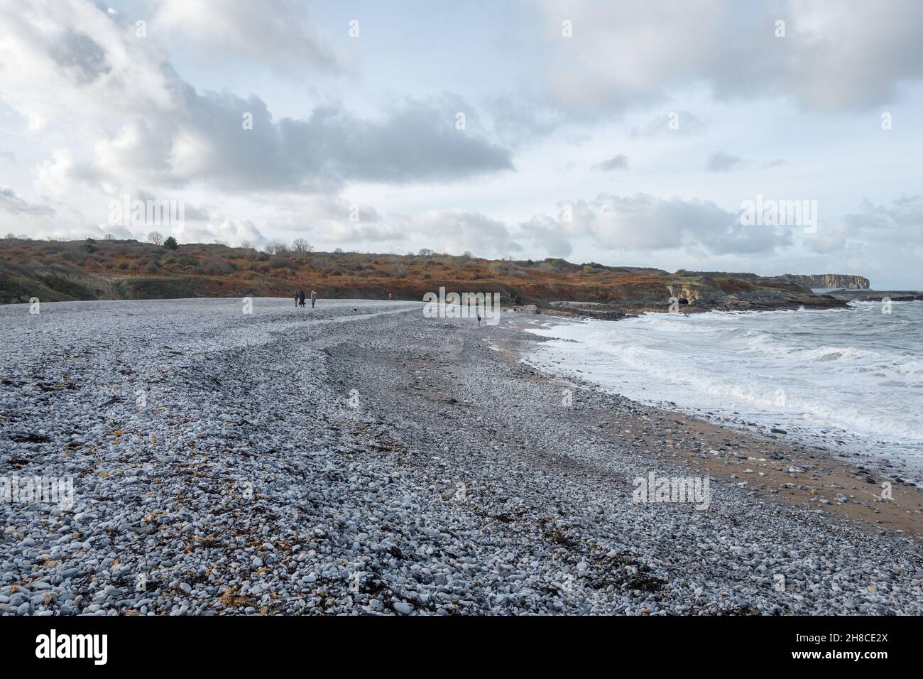 Die Familie genießt einen Spaziergang am Kiesstrand in Penmon, Anglesey, Wales Stockfoto